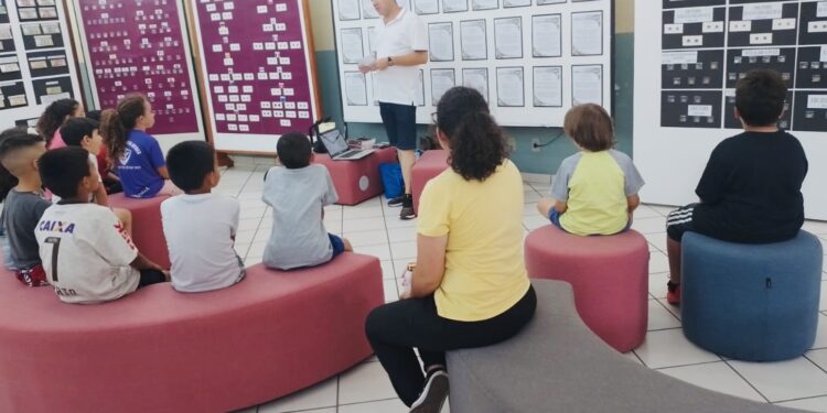 O colecionador Júlio Cesar B. Leme fala sobre a história das moedas para alunos visitantes da biblioteca. (Divulgação)