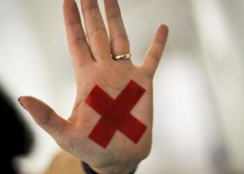 O sinal “X” feito com batom vermelho (ou qualquer outro material) na palma da mão ou em um pedaço de papel, o que for mais fácil, permite que a pessoa treinada reconheça que aquela mulher foi vítima de violência doméstica e, assim, acione a Polícia Militar. (Agência Brasil)