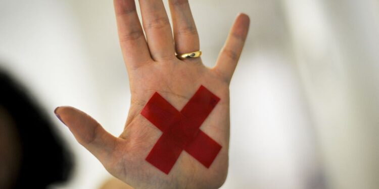 O sinal “X” feito com batom vermelho (ou qualquer outro material) na palma da mão ou em um pedaço de papel, o que for mais fácil, permite que a pessoa treinada reconheça que aquela mulher foi vítima de violência doméstica e, assim, acione a Polícia Militar. (Agência Brasil)