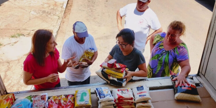 Pessoas com pacotes de alimento. (Divulgação)