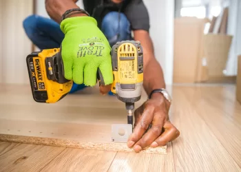 person using dewalt cordless impact driver on brown board