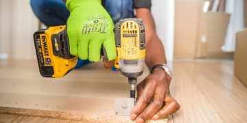 person using dewalt cordless impact driver on brown board